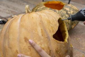 Geschnitzter Halloween-Kürbis, Jack-Laterne, mit Schnitzwerkzeugen. gespenstisches Lachen, gruseliger Kopf. foto