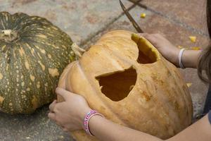 junge Frau mit Kürbiskopf nach dem Abschneiden und Aufsetzen eines Gesichts, Halloween, foto