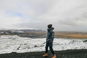 Wandertourist, der eine Schneelandschaft und eine ferne Stadt betrachtet foto