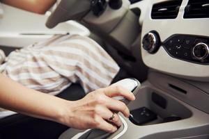 Nahaufnahme der Hand der Frau am Schalthebel in einem modernen Automobil mit weißem Innenraum foto