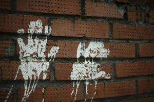 Handabdruck auf Ziegelwand. Palmenabdruck mit weißer Farbe an der Wand. Babyhände in Farbe. foto