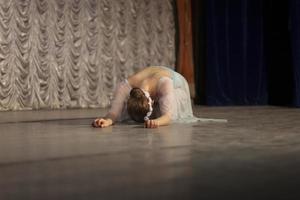 Das Mädchen liegt auf der Bühne. die Ballerina tritt auf. schöne Bewegungen der Tänzerin. foto