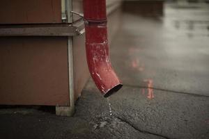 Fallrohr im Gebäude. Wasser fließt vom Dach auf den Asphalt. foto