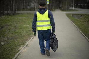 Arbeiter sammelt Müll. Mann trägt Paket. schwarze Tasche in der Hand. foto