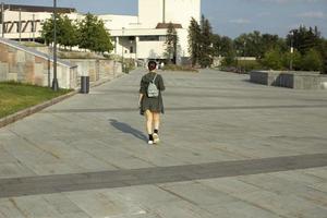 Mädchen geht im Sommer durch den Platz. durch die Stadt laufen. Mädchen mit kleinem Rucksack. foto