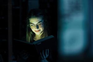 mysteriöses grünes Licht kommt aus dem Buch. Vorstellung von Kreativität. Studentin ist in der Bibliothek. Konzeption von Bildung foto