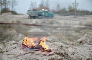 brennende sportschuhe oder turnschuhe in feuer stehen an der sandstrandküste. Sportler ausgebrannt. körperliche anstrengung während des trainingskonzepts foto