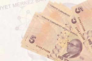 5 türkische Lira-Scheine liegen im Stapel auf dem Hintergrund einer großen halbtransparenten Banknote. abstrakte Darstellung der Landeswährung foto