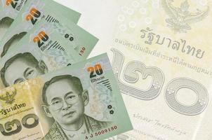 20 thailändische Baht-Scheine liegen im Stapel auf dem Hintergrund einer großen halbtransparenten Banknote. abstrakter betriebswirtschaftlicher hintergrund foto