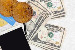 10 US-Dollar-Scheine und goldene Bitcoins mit Smartphone und Kreditkarten. kryptowährungsinvestitionskonzept. Krypto-Mining oder -Handel foto