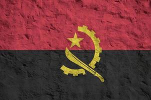 angolanische flagge in hellen farben auf alter reliefputzwand dargestellt. strukturierte Fahne auf rauem Hintergrund foto