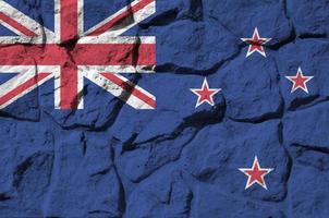 Neuseeland-Flagge in Lackfarben auf der alten Steinmauer in der Nähe dargestellt. strukturiertes banner auf felswandhintergrund foto