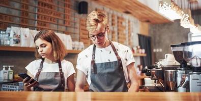 Vorderansicht. zwei junge caféarbeiter drinnen. Geschäfts- und Dienstleistungskonzept foto