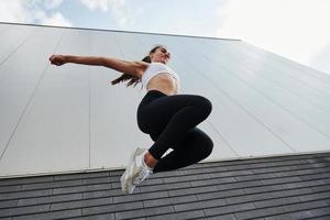 Untersicht. junge sportlerin, die tagsüber parkour in der stadt macht foto