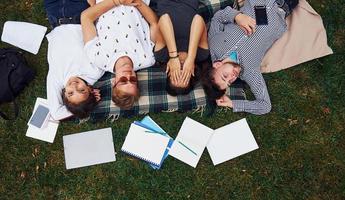 gute Erholung haben. Gruppe junger Studenten in Freizeitkleidung auf grünem Gras tagsüber foto