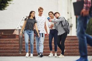 Sprechendes Selfie beim Spazierengehen. gruppe junger studenten in legerer kleidung tagsüber in der nähe der universität foto