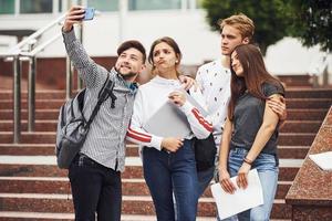 Stehen und Selfie machen. gruppe junger studenten in legerer kleidung tagsüber in der nähe der universität foto