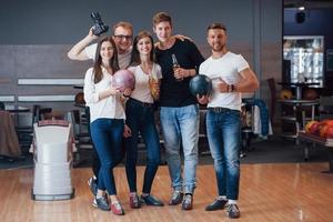 mit Fotograf. Junge, fröhliche Freunde haben an ihren Wochenenden Spaß im Bowlingclub foto