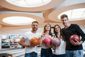 hübsche Leute. Junge, fröhliche Freunde haben an ihren Wochenenden Spaß im Bowlingclub foto