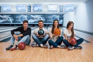 immer zusammen. Junge, fröhliche Freunde haben an ihren Wochenenden Spaß im Bowlingclub foto