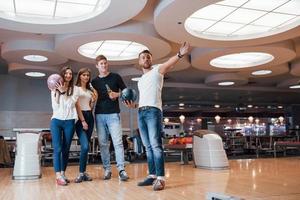 warten auf den Spielstart. Junge, fröhliche Freunde haben an ihren Wochenenden Spaß im Bowlingclub foto