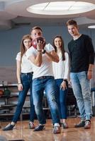 Junge, fröhliche Freunde haben an ihren Wochenenden Spaß im Bowlingclub foto