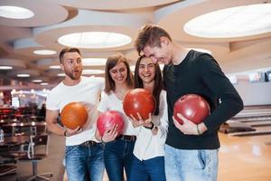 Witze machen. Junge, fröhliche Freunde haben an ihren Wochenenden Spaß im Bowlingclub foto