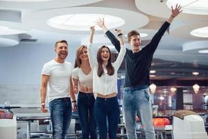 danke für das tolle spiel. Junge, fröhliche Freunde haben an ihren Wochenenden Spaß im Bowlingclub foto