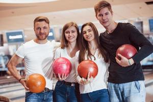 beste Freunde. Junge, fröhliche Leute haben an ihren Wochenenden Spaß im Bowlingclub foto