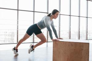 in schwarzen Shorts und grauem Hemd. Sportliche junge Frau hat morgens einen Fitnesstag im Fitnessstudio foto