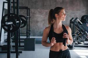 stehend mit Springseil in den Händen. Foto einer wunderschönen blonden Frau im Fitnessstudio an ihrer Wochenendzeit