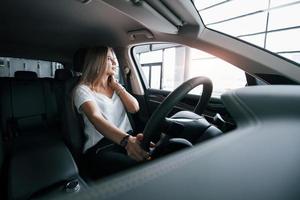 natürliches Tageslicht. Mädchen im modernen Auto im Salon. tagsüber drinnen. Neuwagen kaufen foto