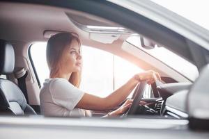 mit Uhr zur Hand. Mädchen im modernen Auto im Salon. tagsüber drinnen. Neuwagen kaufen foto