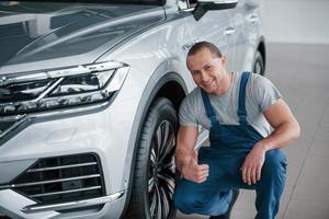 gut gemacht. nach fachmännischer Reparatur. Mann, der ein perfekt poliertes, silberfarbenes Auto betrachtet foto