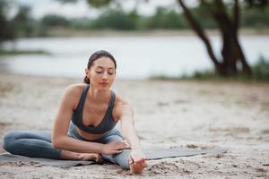 einfaches Aufwärmen. brünette mit schöner körperform in sportlicher kleidung haben einen fitnesstag am strand foto