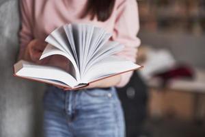 viele Seiten. Mädchen, das in der Bibliothek voller Bücher nach Informationen sucht foto