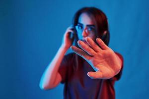 spühr die Musik. Studioaufnahme drinnen mit Neonlicht. Porträt eines schönen jungen Mädchens foto