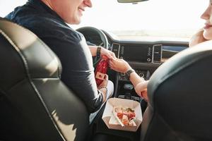 leckeres Essen. Schöne Menschen sitzen an ihren Wochenenden im modernen Auto foto