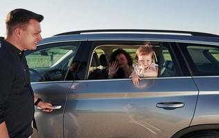 Hallo, Geste. Schöne Menschen sitzen an ihren Wochenenden im modernen Auto foto