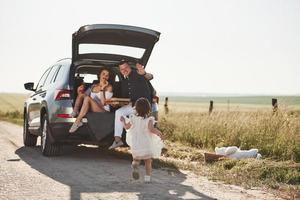 mutter und väter essen pizza. Schöne Menschen sitzen an ihren Wochenenden im modernen Auto foto