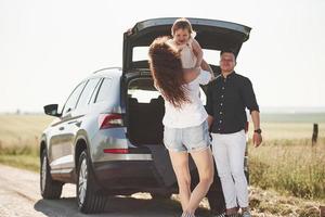 familie hat eine gute zeit auf dem land in der nähe von silberautos bei sonnenuntergang foto