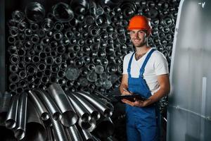 lächelt für die Kamera. Mann in Uniform arbeitet an der Produktion. Industrielle moderne Technologie foto