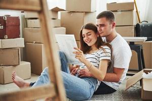 Dokument lesen. fröhliches junges Paar in ihrer neuen Wohnung. Vorstellung von Bewegung foto