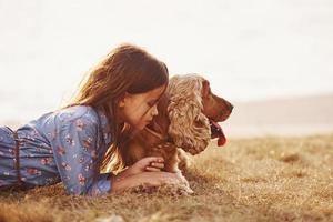 warm und ruhig. süßes kleines Mädchen geht an sonnigen Tagen mit ihrem Hund im Freien spazieren foto