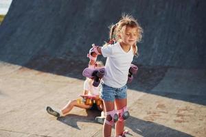 neuen Schlittschuh ausprobieren. Zwei süße weibliche Kinder haben Spaß im Freien im Park foto