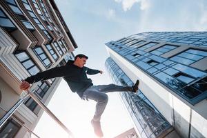 junger Mann, der tagsüber Parkour in der Stadt macht. Konzeption von Extremsportarten foto