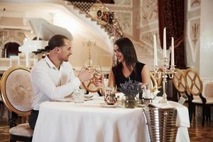 Dieser Toast ist für uns. Schönes Paar hat abends ein romantisches Abendessen im Luxusrestaurant foto