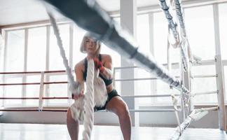 am Boxring. Blonde Sportlerin trainiert mit Seilen im Fitnessstudio. starkes Weib foto