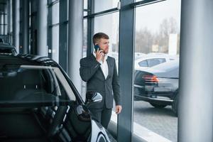 wichtiger Anruf. moderner stilvoller bärtiger geschäftsmann im autosalon foto