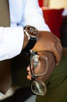Person, die eine Brille hält und eine Armbanduhr trägt foto